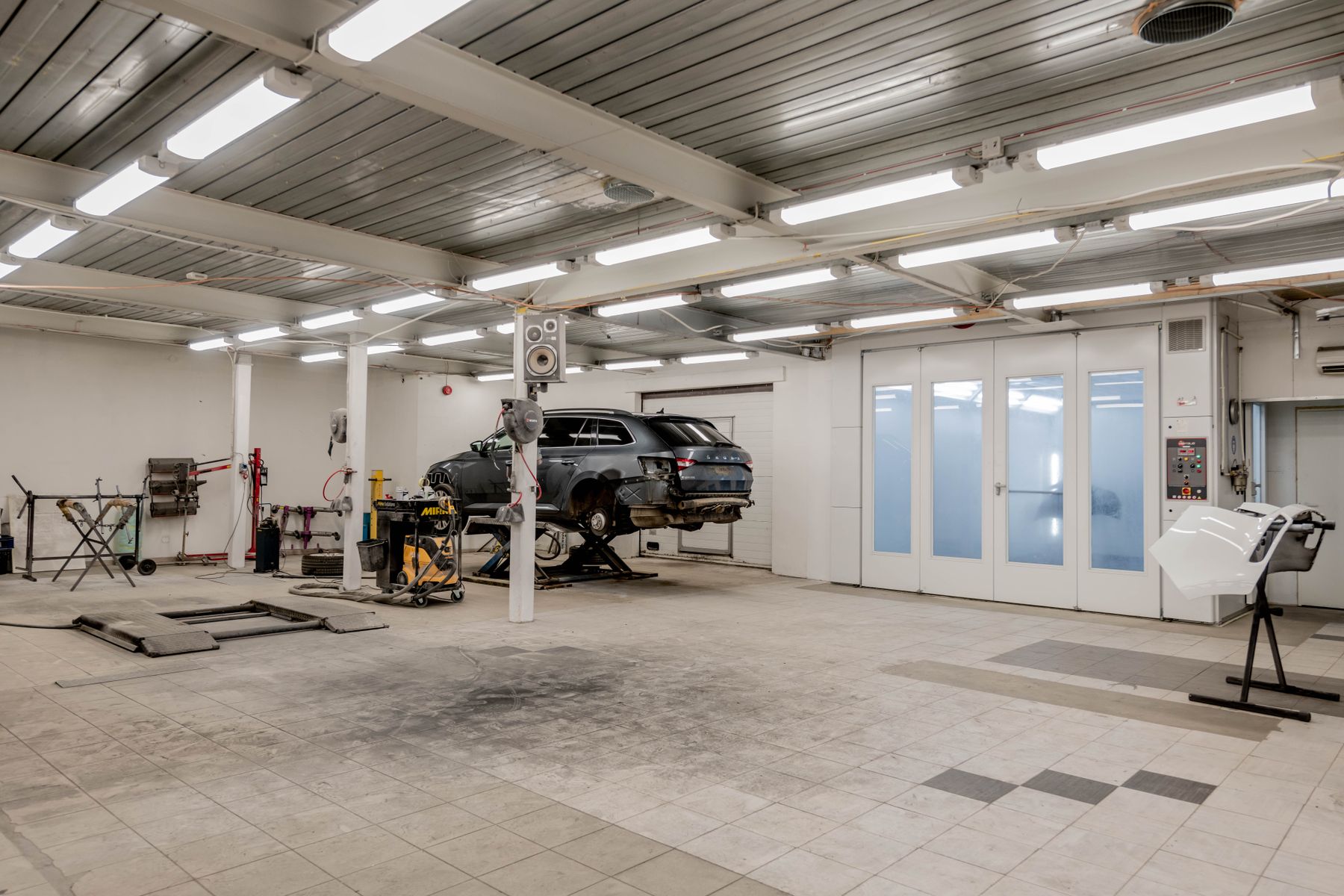 Helle Werkstatthalle mit Hebebühne und Fahrzeug bei der Instandsetzung