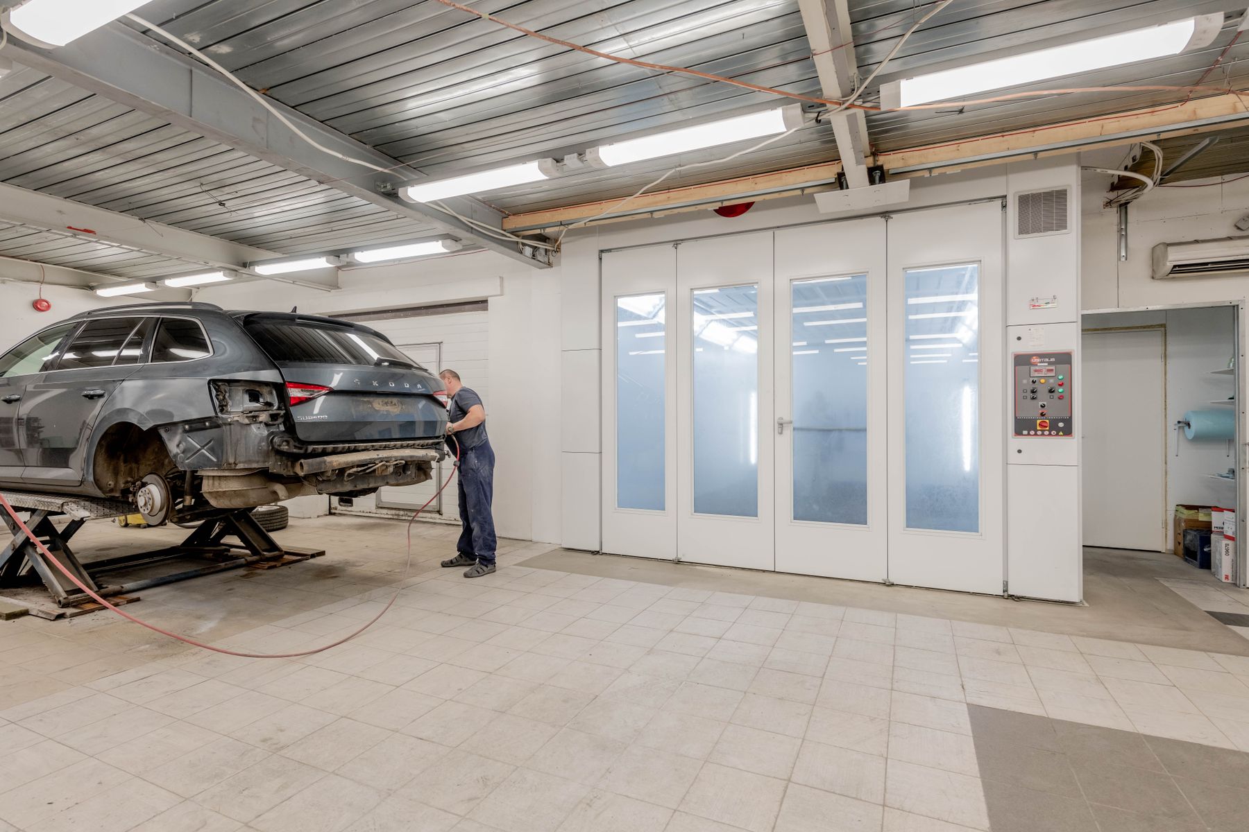 Karosseriebauer bei der Arbeit in der hellen Werkstatthalle